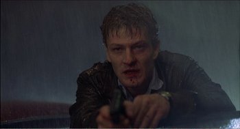 Movie still from “Stormy Monday” (1988), directed by Mike Figgis – A man in a leather jacket is holding a gun; Close Up shot, Low angle