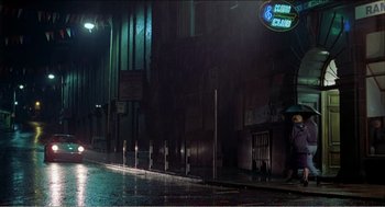 Movie still from “Stormy Monday” (1988), directed by Mike Figgis – A person with an umbrella on a rainy night; Extreme Wide shot, Low angle