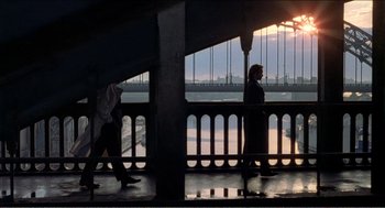 Movie still from “Stormy Monday” (1988), directed by Mike Figgis – Two people walking on a bridge at sunset; Extreme Wide shot, High angle