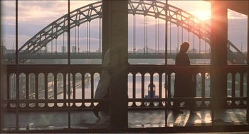 Movie still from “Stormy Monday” (1988), directed by Mike Figgis – Two people are walking on a balcony near a bridge; Extreme Wide shot, High angle