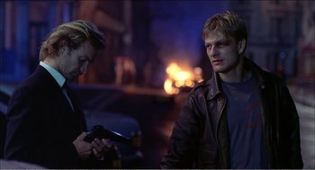 Movie still from “Stormy Monday” (1988), directed by Mike Figgis – Two men standing next to each other on a city street; Medium shot, Over the shoulder angle