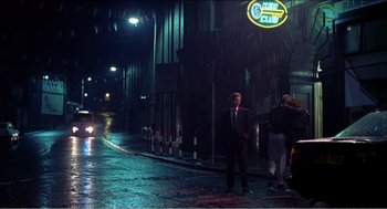 Movie still from “Stormy Monday” (1988), directed by Mike Figgis – A man in a business suit standing in the middle of the street; Wide shot, Low angle