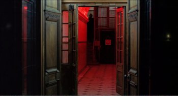 Movie still from “Stormy Monday” (1988), directed by Mike Figgis – A red lit room with a person standing in the doorway; Extreme Wide shot, Low angle