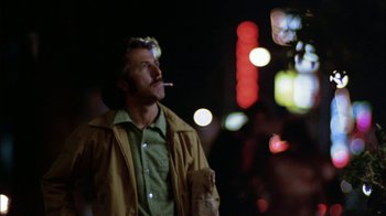 Movie still from “Straight Time” (1978), directed by Ulu Grosbard – A man is smoking a cigarette while standing on the street; Close Up shot, Low angle