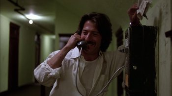 Movie still from “Straight Time” (1978), directed by Ulu Grosbard – A man talking on a phone while wearing a white shirt; Medium shot, Low angle