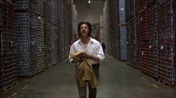 Movie still from “Straight Time” (1978), directed by Ulu Grosbard – A man walking through a warehouse holding a jacket; Medium shot, Low angle