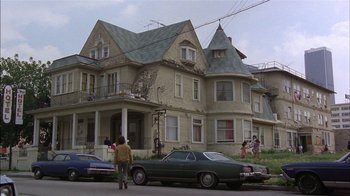 Movie still from “Straight Time” (1978), directed by Ulu Grosbard – A man standing in front of a car in front of a house; Wide shot, Low angle