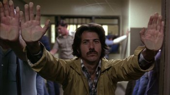 Movie still from “Straight Time” (1978), directed by Ulu Grosbard – A man in a yellow raincoat with his arms outstretched; Medium shot, Low angle