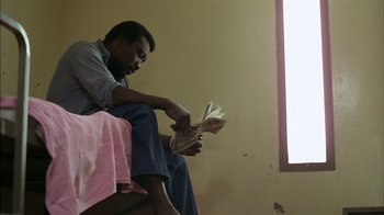 Movie still from “Straight Time” (1978), directed by Ulu Grosbard – A man sitting on the ground reading a book; Medium shot, Low angle