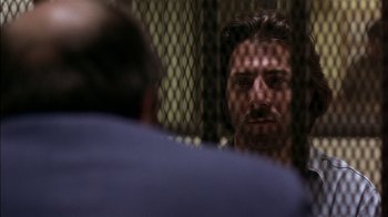 Movie still from “Straight Time” (1978), directed by Ulu Grosbard – A man stares into the camera through a chain link fence; Close Up shot, Over the shoulder angle