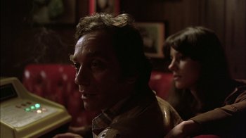 Movie still from “Straight Time” (1978), directed by Ulu Grosbard – A person sitting on a couch; Close Up shot, Over the shoulder angle