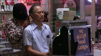 Movie still from “Straight Time” (1978), directed by Ulu Grosbard – A man with headphones on his ears is listening to music; Medium shot, Over the shoulder angle