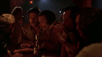 Movie still from “Straight Time” (1978), directed by Ulu Grosbard – A group of people sitting at a table drinking; Medium shot, Over the shoulder angle
