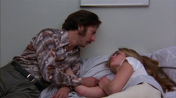 Movie still from “Straight Time” (1978), directed by Ulu Grosbard – A man and a woman laying in a bed together; Medium shot, Low angle