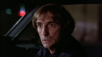 Movie still from “Straight Time” (1978), directed by Ulu Grosbard – A person with a car in the background; Close Up shot, Low angle