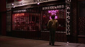 Movie still from “Straight Time” (1978), directed by Ulu Grosbard – A man standing in front of a store on a sidewalk; Wide shot, Low angle