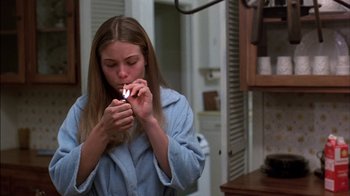 Movie still from “Straight Time” (1978), directed by Ulu Grosbard – A woman smoking a cigarette while wearing a blue robe; Medium shot, High angle