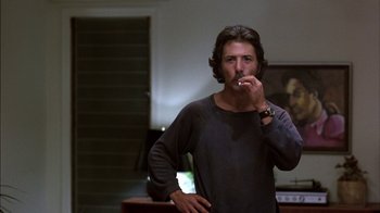 Movie still from “Straight Time” (1978), directed by Ulu Grosbard – A man standing in a living room smoking a cigarette; Medium shot, Low angle