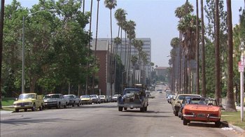 Movie still from “Straight Time” (1978), directed by Ulu Grosbard – Cars driving down a street lined with palm trees; Extreme Wide shot, Low angle