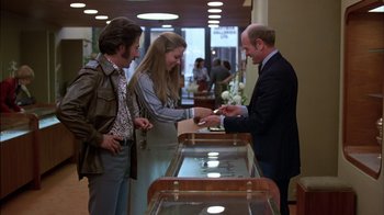 Movie still from “Straight Time” (1978), directed by Ulu Grosbard – Two men and a woman at a jewelry store; Medium shot, High angle