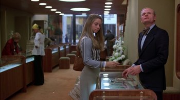 Movie still from “Straight Time” (1978), directed by Ulu Grosbard – A woman standing in front of a display case; Medium shot, Over the shoulder angle