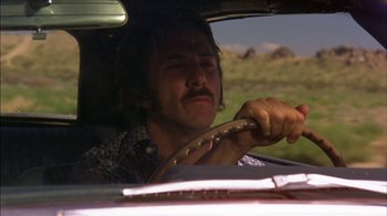 Movie still from “Straight Time” (1978), directed by Ulu Grosbard – A man driving a car in the middle of the day; Close Up shot, Low angle