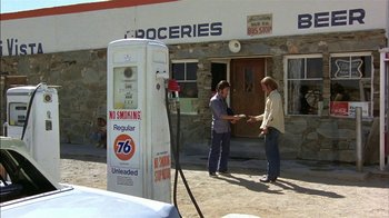 Movie still from “Straight Time” (1978), directed by Ulu Grosbard – Two men shaking hands in front of a gas station; Wide shot, High angle