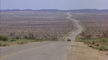 Movie still from “Straight Time” (1978), directed by Ulu Grosbard – A car driving down the middle of a road; Extreme Wide shot, High angle