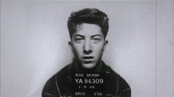 Movie still from “Straight Time” (1978), directed by Ulu Grosbard – An old black and white photo of a man in a police mugshot; Extreme Close Up shot, Overhead angle