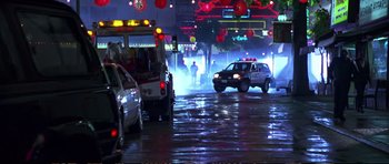 Movie still from “Strange Days” (1995), directed by Kathryn Bigelow – A police car driving down a street in the rain; Extreme Wide shot, Low angle
