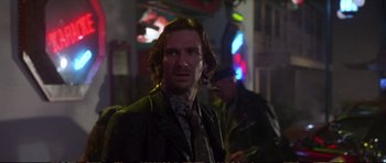 Movie still from “Strange Days” (1995), directed by Kathryn Bigelow – A man in a jacket and tie standing in front of a neon sign; Close Up shot, Over the shoulder angle