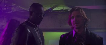 Movie still from “Strange Days” (1995), directed by Kathryn Bigelow – Two men standing next to each other in front of a purple light; Medium shot, Low angle