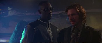 Movie still from “Strange Days” (1995), directed by Kathryn Bigelow – A man in a jacket and sunglasses standing next to another man in a jacket; Medium shot, Low angle