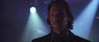 Movie still from “Strange Days” (1995), directed by Kathryn Bigelow – A man with long blonde hair standing in front of lights; Close Up shot, Low angle