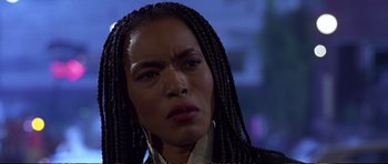 Movie still from “Strange Days” (1995), directed by Kathryn Bigelow – A person with braids wearing a suit; Close Up shot, Low angle
