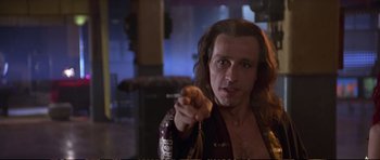 Movie still from “Strange Days” (1995), directed by Kathryn Bigelow – A man with long brown hair is holding a string; Close Up shot, Low angle