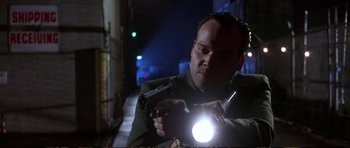 Movie still from “Strange Days” (1995), directed by Kathryn Bigelow – A man holding a gun with a flashlight in his hand; Close Up shot, Low angle