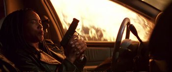 Movie still from “Strange Days” (1995), directed by Kathryn Bigelow – A person holding a gun while sitting in a car; Close Up shot, Low angle