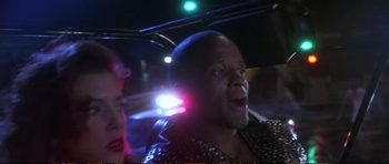 Movie still from “Strange Days” (1995), directed by Kathryn Bigelow – A man in a leather jacket is in the back of a car; Close Up shot, Over the shoulder angle