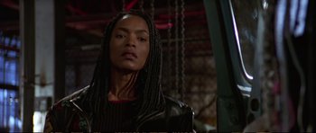 Movie still from “Strange Days” (1995), directed by Kathryn Bigelow – A woman in a leather jacket with long braids; Close Up shot, Low angle