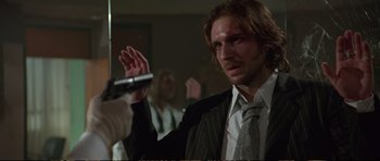 Movie still from “Strange Days” (1995), directed by Kathryn Bigelow – A man in a suit and tie holding a microphone; Close Up shot, Low angle