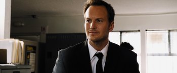 Movie still from “Stretch” (2014), directed by Joe Carnahan – A person wearing a suit and tie; Close Up shot, Over the shoulder angle