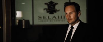 Movie still from “Stretch” (2014), directed by Joe Carnahan – A person wearing a suit and tie; Close Up shot, Over the shoulder angle