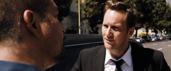 Movie still from “Stretch” (2014), directed by Joe Carnahan – A man wearing a suit and tie talking to another man in a suit; Close Up shot, Over the shoulder angle