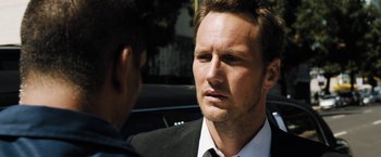 Movie still from “Stretch” (2014), directed by Joe Carnahan – A man wearing a suit and tie talking to another man in front of a car; Close Up shot, Over the shoulder angle