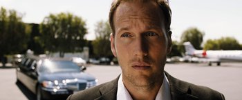 Movie still from “Stretch” (2014), directed by Joe Carnahan – A person wearing a suit and tie; Close Up shot, Low angle