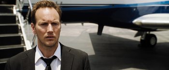 Movie still from “Stretch” (2014), directed by Joe Carnahan – A person wearing a suit and tie; Close Up shot, Low angle