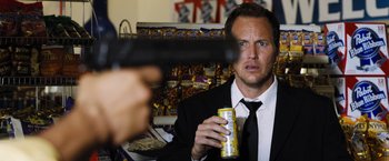 Movie still from “Stretch” (2014), directed by Joe Carnahan – A man in a suit and tie holding a can and a gun; Close Up shot, Over the shoulder angle