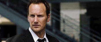 Movie still from “Stretch” (2014), directed by Joe Carnahan – A person wearing a suit and tie; Close Up shot, Low angle