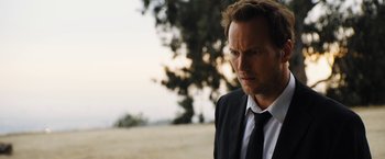 Movie still from “Stretch” (2014), directed by Joe Carnahan – A person wearing a suit and tie; Close Up shot, Over the shoulder angle